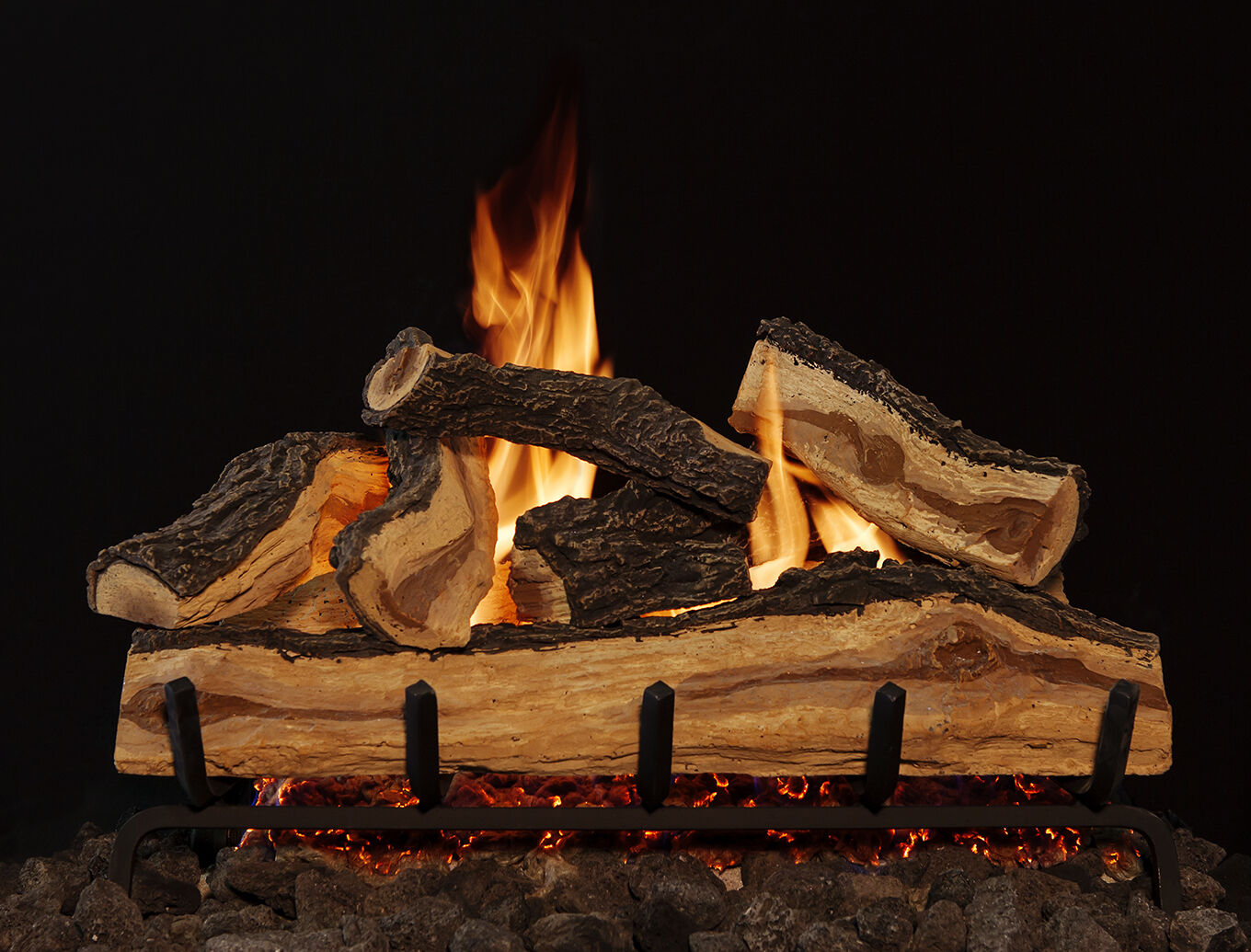 A close-up view of a traditional, oak-style gas log set with natural bark detailing and full, golden flames.